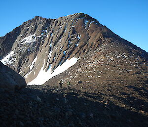 picture of a rocky mountain range with expeditioners walking along a saddle - far into the distance