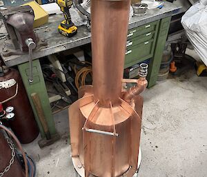 A picture of a large and very new brass melt bell in the plumber's workshop.