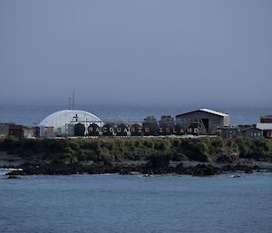 A view of Macquarie Island's sign, written across eight brown fuel drums, from the water.