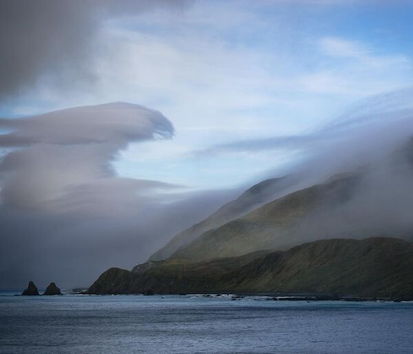 A large cloud bank swirls over the coastal edge of Macqurie Island.