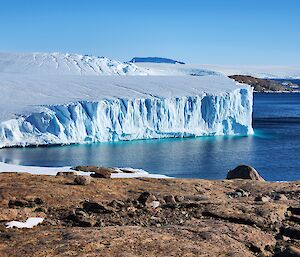 A photo of an Ice shelf on the coastline, with mountain range well into the distance