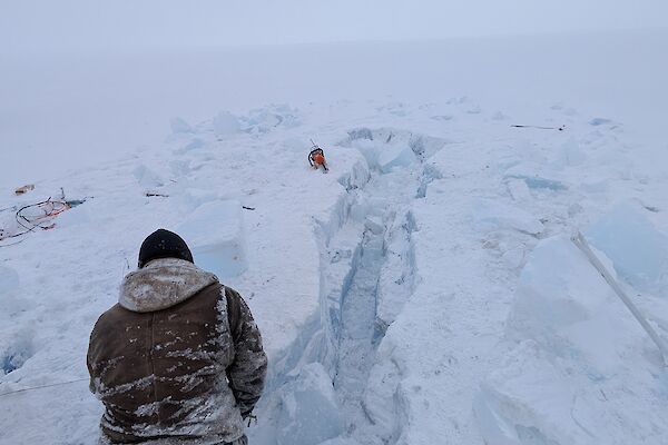 A man digging a hole in the ice