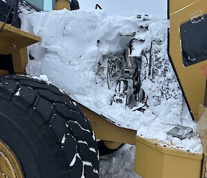 The engine bay of a piece of plant machinery, with the engine compartment totally frozen with ice and snow.