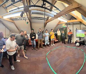 A wide angle shot of expeditioners around the two-up ring in Biscoe Hut, waiting for the toss.