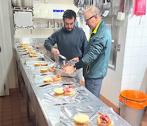 Two expeditioners preparing egg and bacon rolls in the kitchen, ready for eating later in the day.