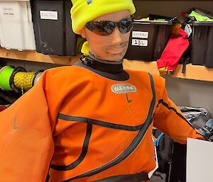 An orange-clad dummy wearing sunglasses and a yellow beanie