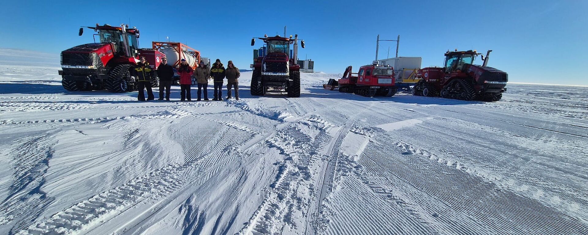 three large tractors sitting on the snow and ice in Antarctica