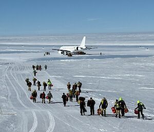 passengers walk towards a passenger jet across the ice runway