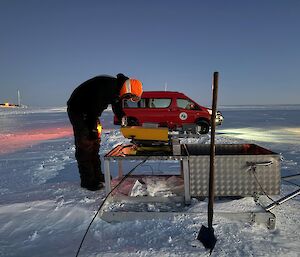 a staff member stands in front of a red van on the ice runway