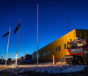 The sun rises at Davis station in Antarctica, with the Australian and New Zealand flags flying in the foreground