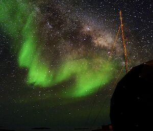green aurora against a milky way, starry backdrop - taken near a station's ANARESAT building