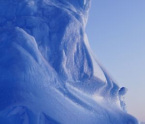 picture of a large pure blue-ice feature above the ground, with cliffs and features shaped by a harsh environment