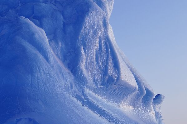 picture of a large pure blue-ice feature above the ground, with cliffs and features shaped by a harsh environment
