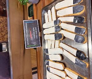 A tray of biscuits that look like white lightsabres with black handles