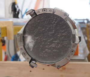 The end of an ice core inside a drill barrel. Bubble of air are visible in the ice.