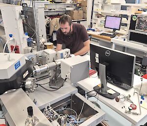 A man standing in a laboratory filled with high-tech scientific equipment used to measure atmospheric gases.
