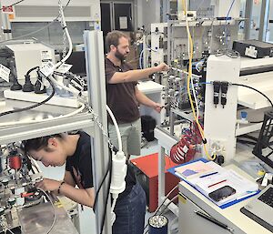 A man and a woman working in a laboratory filled with high-tech scientific equipment used to measure atmospheric gases.