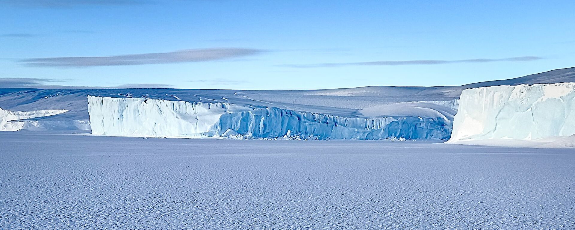 deep blue glacier tongue surrounded by coastal ice cliffs - photo taken from the sea ice