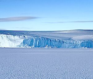 deep blue glacier tongue surrounded by coastal ice cliffs - photo taken from the sea ice