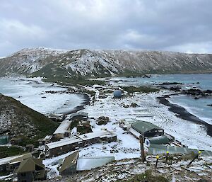 A view of the Macquarie Island research station from above, with the ocean on both sides and the land covered in snow