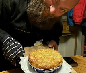 A smiling man holding a pie