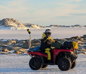 A person in a helmet riding a quad bike on the ice