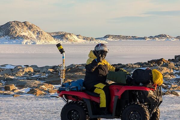 A person in a helmet riding a quad bike on the ice