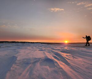 A person at sunset on an icy plain