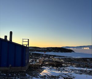 Picture taken of the side of the blue balloon building, with snow, sea ice and islands in the background