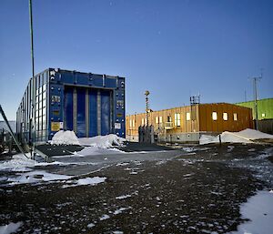 A blue building with large front doors, alongside the station's yellow operations building
