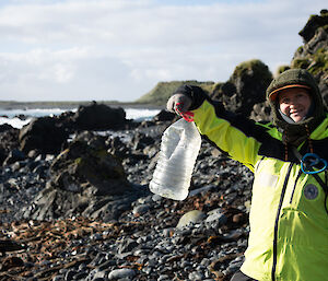 A person holding a plastic bottle that has washed up on the Macquarie Island shore