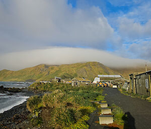 A cloud draped over the top of a mountain, with station buildings in the foreground.