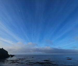 Horizontal streaks of clouds above the ocean.