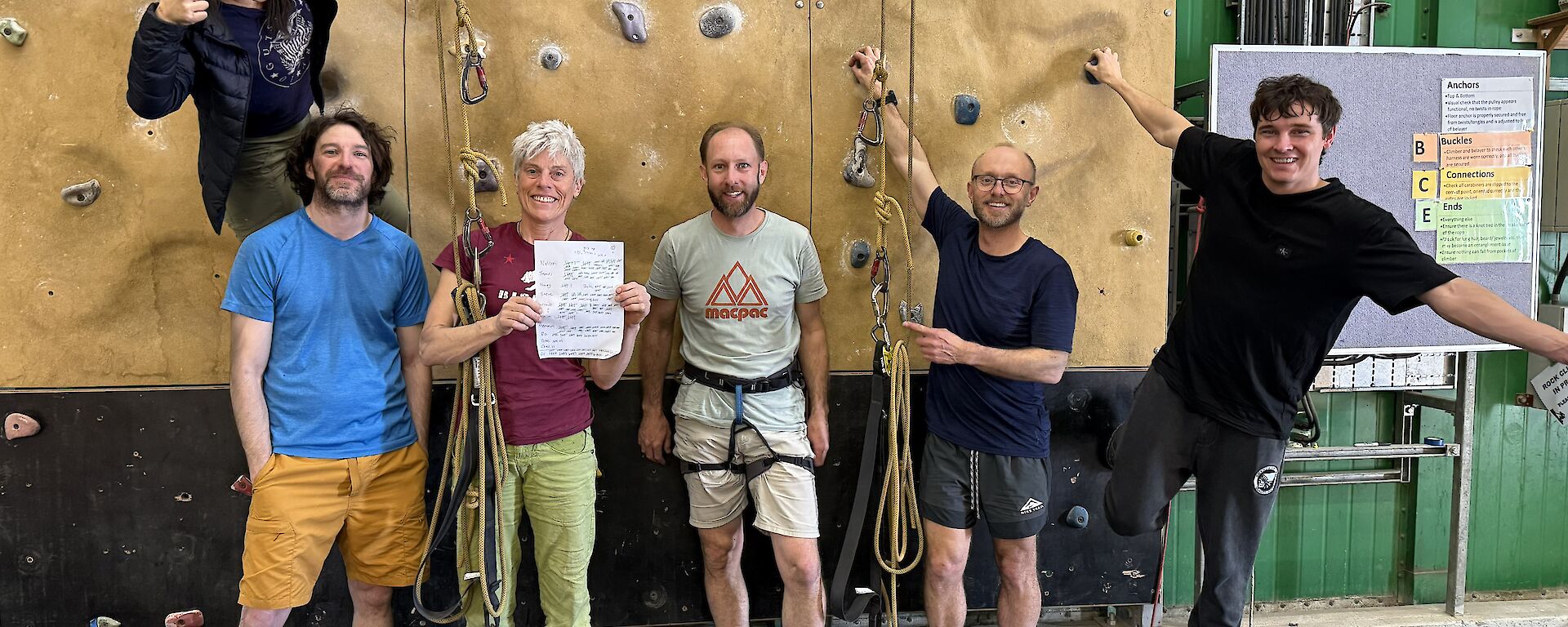 6 people pose happily in front of an indoor climbing wall