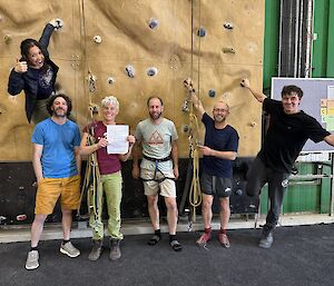 6 people pose happily in front of an indoor climbing wall