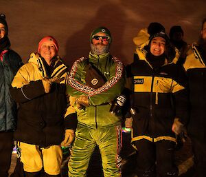Five expeditioners in cold weather gear, outside at night smiling at the camera