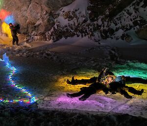 A group of expeditioners on the ice at night, surrounded by coloured lights
