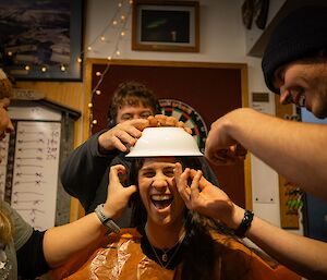 A woman with a bowl on her head as three station hairdressers begin cutting her hair