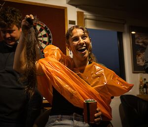 A woman holding up a long ponytail of her own hair as she undergoes a haircut to raise money for conservation.
