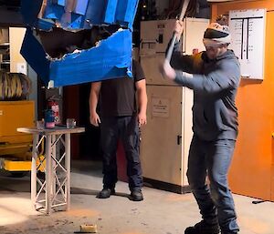 A blindfolded person hits a pinata in a shed