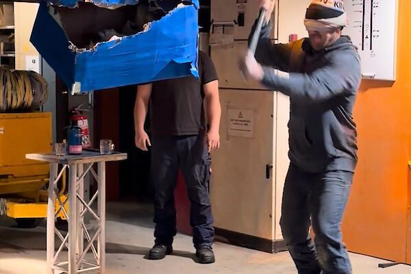 A blindfolded person hits a pinata in a shed