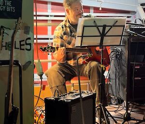 A man playing guitar in a studio setting