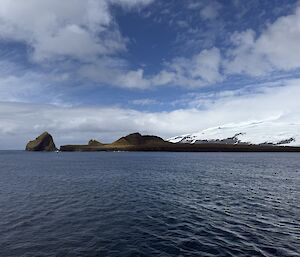 Rugged rocky coastline with snow covered volcano in the background