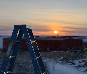 A ladder overlooking the station's main accommodation building, with the sun setting in the background