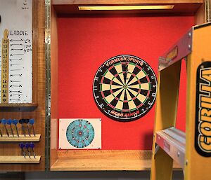 A ladder propped up in front of the station's darts board, with three darts in the 20