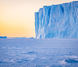 A ground-level photo capturing the corner of the tabular iceberg with other bergs in the distance.