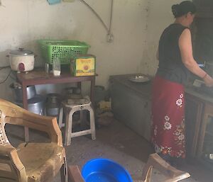 A lady stands next to a stove inside a rudimentary kitchen in Nepal