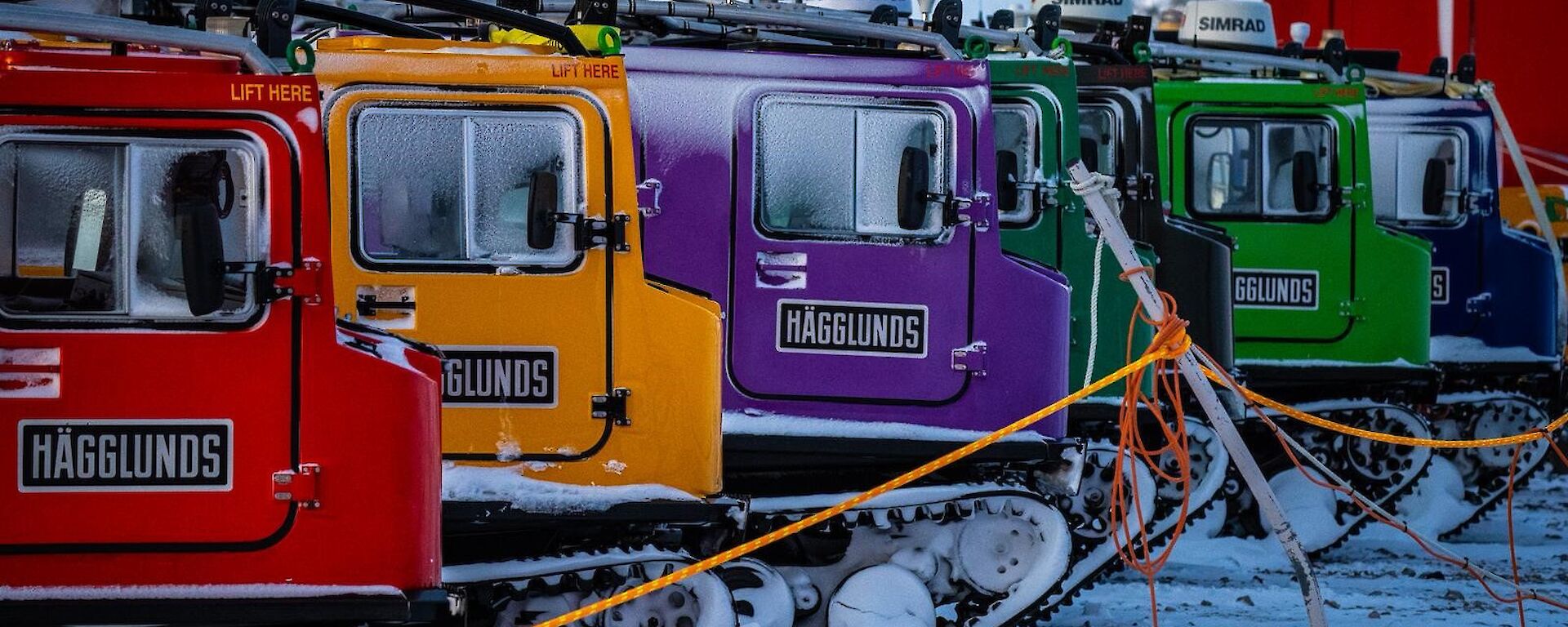Six different coloured hagglund vehicles in a row.