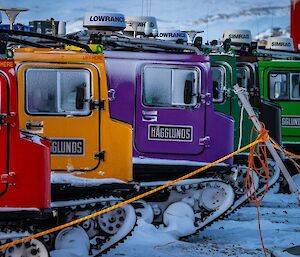 Six different coloured hagglund vehicles in a row.