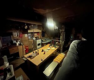 A dimly lit kitchen and dining room inside a hut.